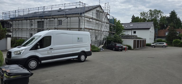 White commercial van parked on asphalt lot in front of building under scaffolding construction